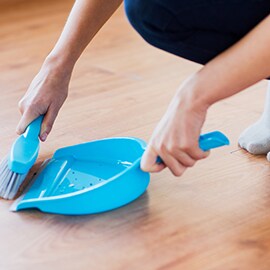 person sweeping the floor with small broom and dustpan