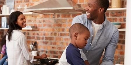 Woman standing at her recently cleaned stove smiling at her husband.