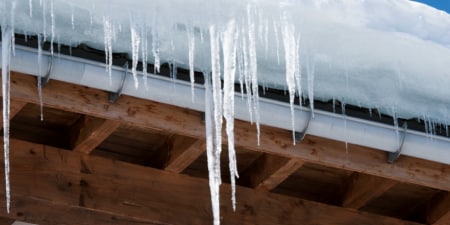 Closeup of a large amount of icicles hanging from a roof in winter.