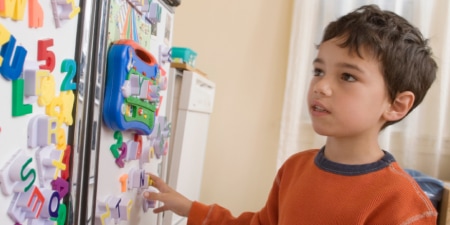 Child looking at the refrigerator covered with magnetic letters, numbers and art work from school.