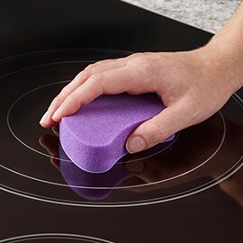 person cleaning an electric stovetop