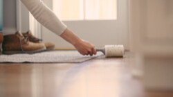 Person using a Scotch-Brite™ Brand lint roller to pick up change off the floor 
