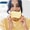 Woman in a yellow shirt playfully holds a sponge to her face