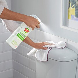 person spraying toilet with scotch brite one step cleaner and disinfectant