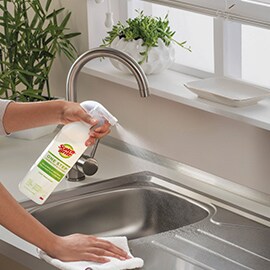 person spraying kitchen sink with scotch brite one step cleaner and disinfectant