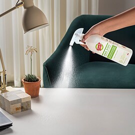 person spraying desk with scotch brite one step cleaner and disinfectant