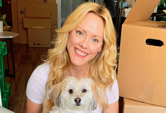 Une femme qui sourit avec un petit chien.
