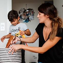 woman and boy putting objects in a cloth bin