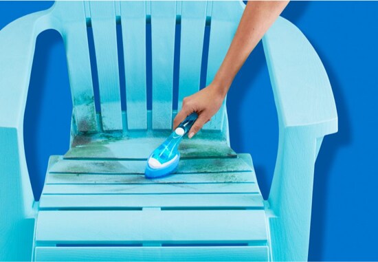 Une personne qui nettoie une chaise de patio sale avec une Brosse à vaisselle Scotch-Brite®.
