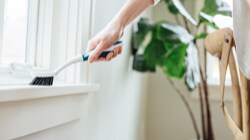 Person cleaning a window ledge with a Scotch-Brite™ Brand scrub brush 
