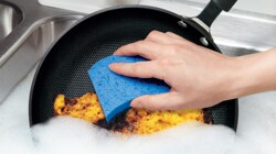 Person cleaning a fry pan with a blue Scotch-Brite™ Brand sponge
