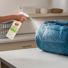 person spraying gym bag with scotch brite one step cleaner and disinfectant